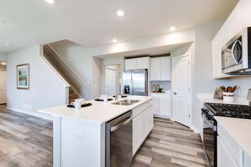 Thoughtfully-designed, modern & fresh describes this kitchen. Equipped with stainless steel appliances, quartz countertops & a large island, this kitchen adds distinction & character to the home. Photo of model home, color & options may vary.