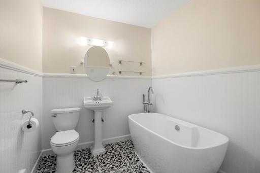 The remodeled full bath is a highlight, with crisp white water-resistant wainscoting, decorative flooring, a pedestal sink and freestanding soaking tub with handheld sprayer.