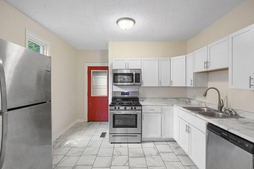 The bright kitchen features white cabinetry and stainless-steel appliances.