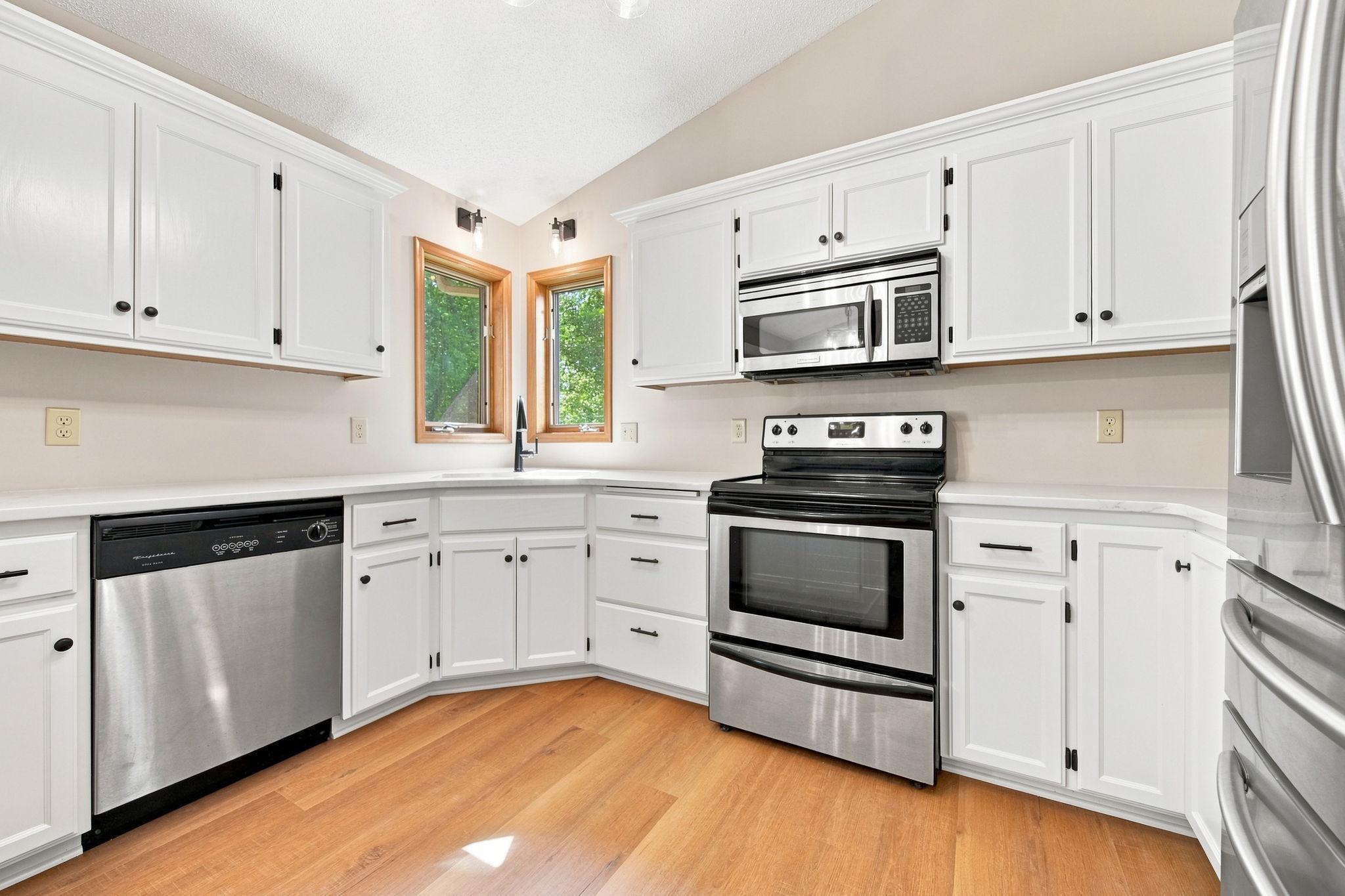 Kitchen features new lighting, freshly painted cabinets, and new quartz countertops.