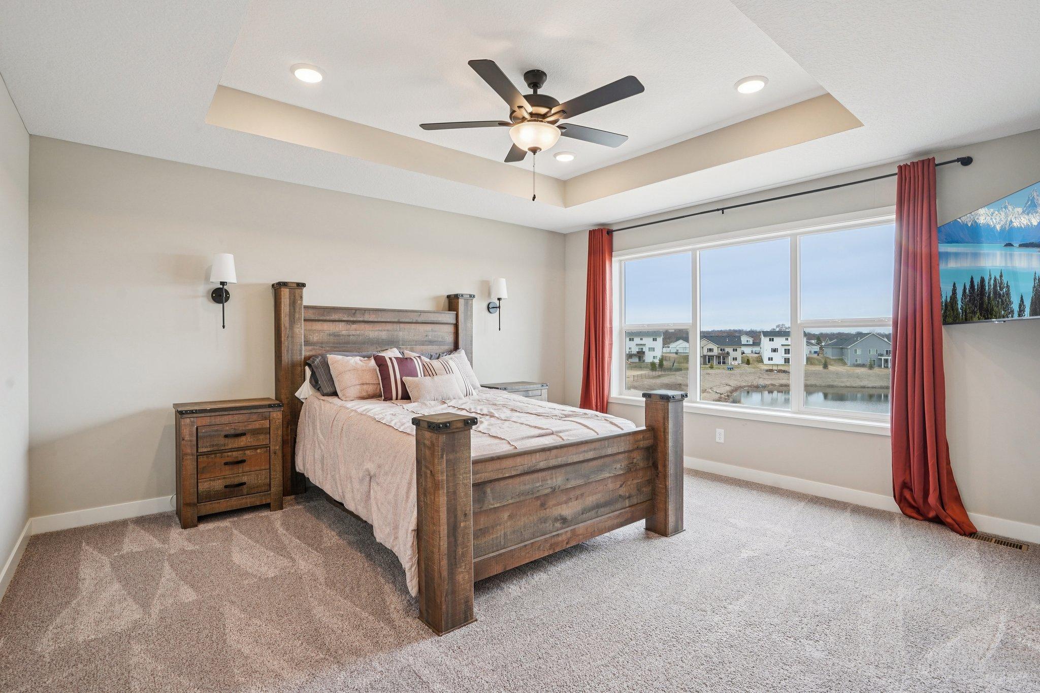 Gorgeous primary suite with tray ceiling and a wall of windows.