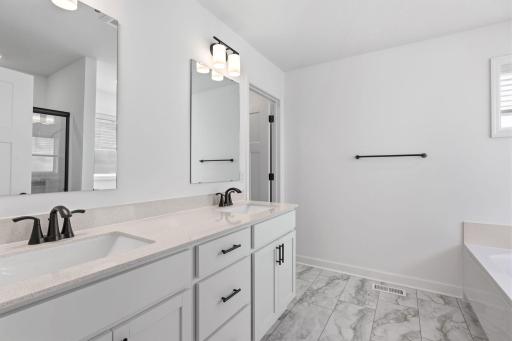 Quartz countertops, plate-glass mirrors, raised-height cabinets and MoenÂ® Glyde faucets unite at this oversized vanity