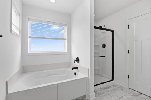 A glass-enclosed shower with Sterling Vikrell surround, built-in seating and an oversized shower head are featured in the bathroom