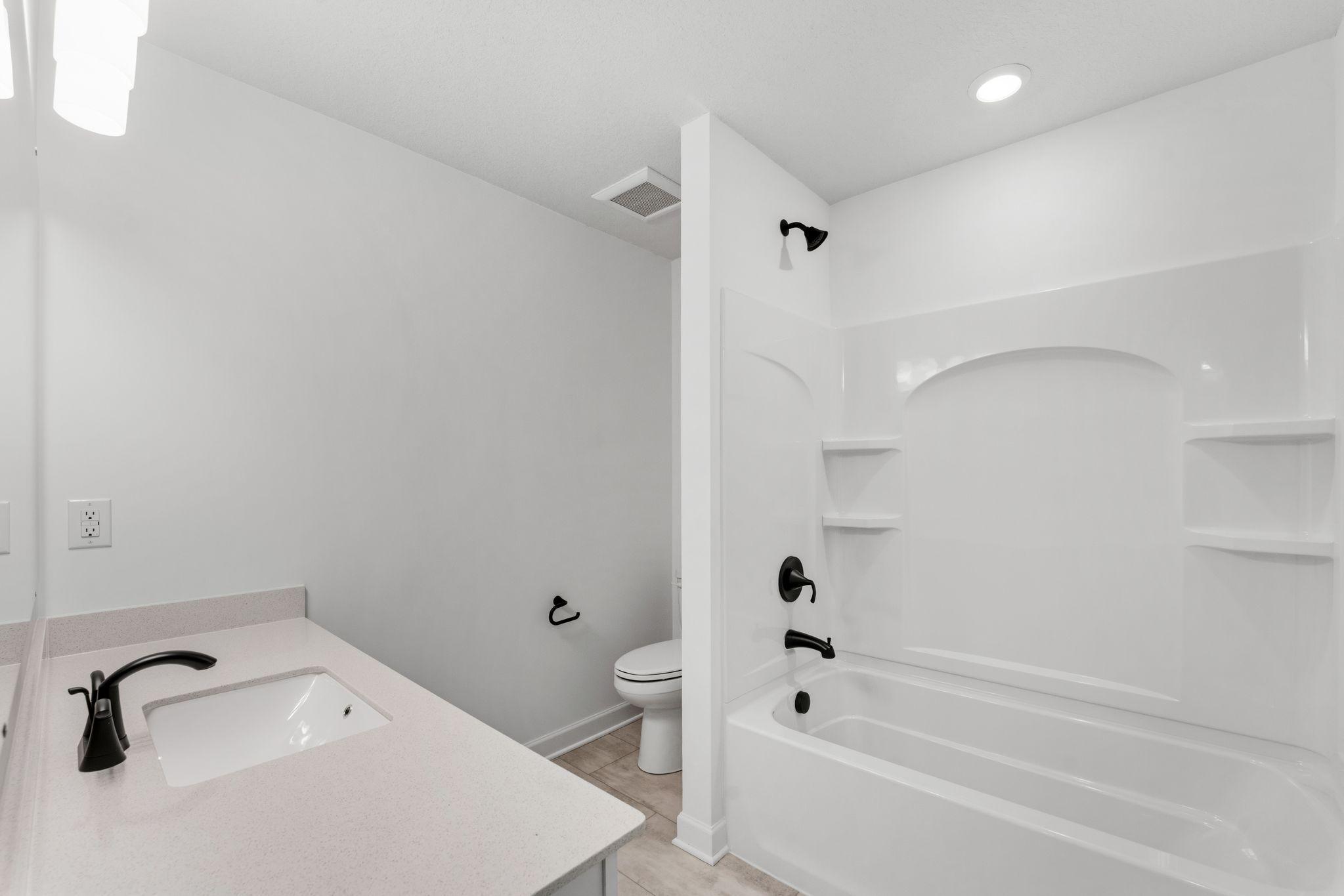 This shared full bathroom includes a full-width vanity mirror and a shower-tub combination.