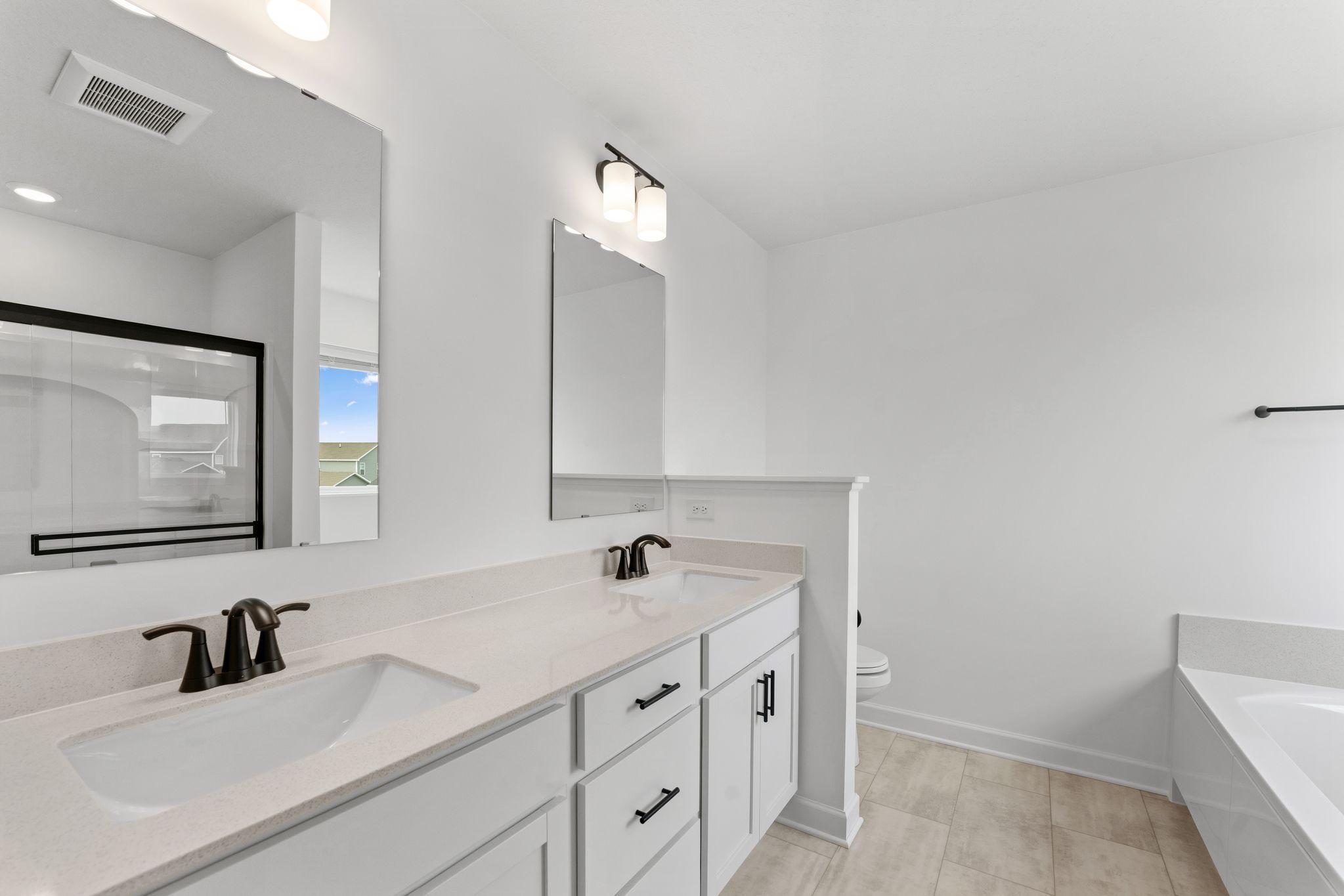 Dual sinks, a glass-enclosed shower and separate soaking tub are included in the en-suite bathroom