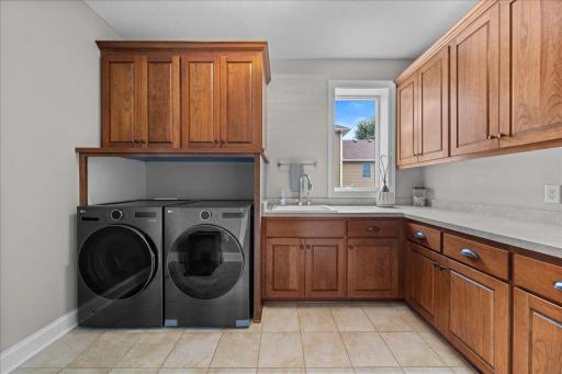 Laundry room with cabinetry, counter space and utility sink makes the chore easy.