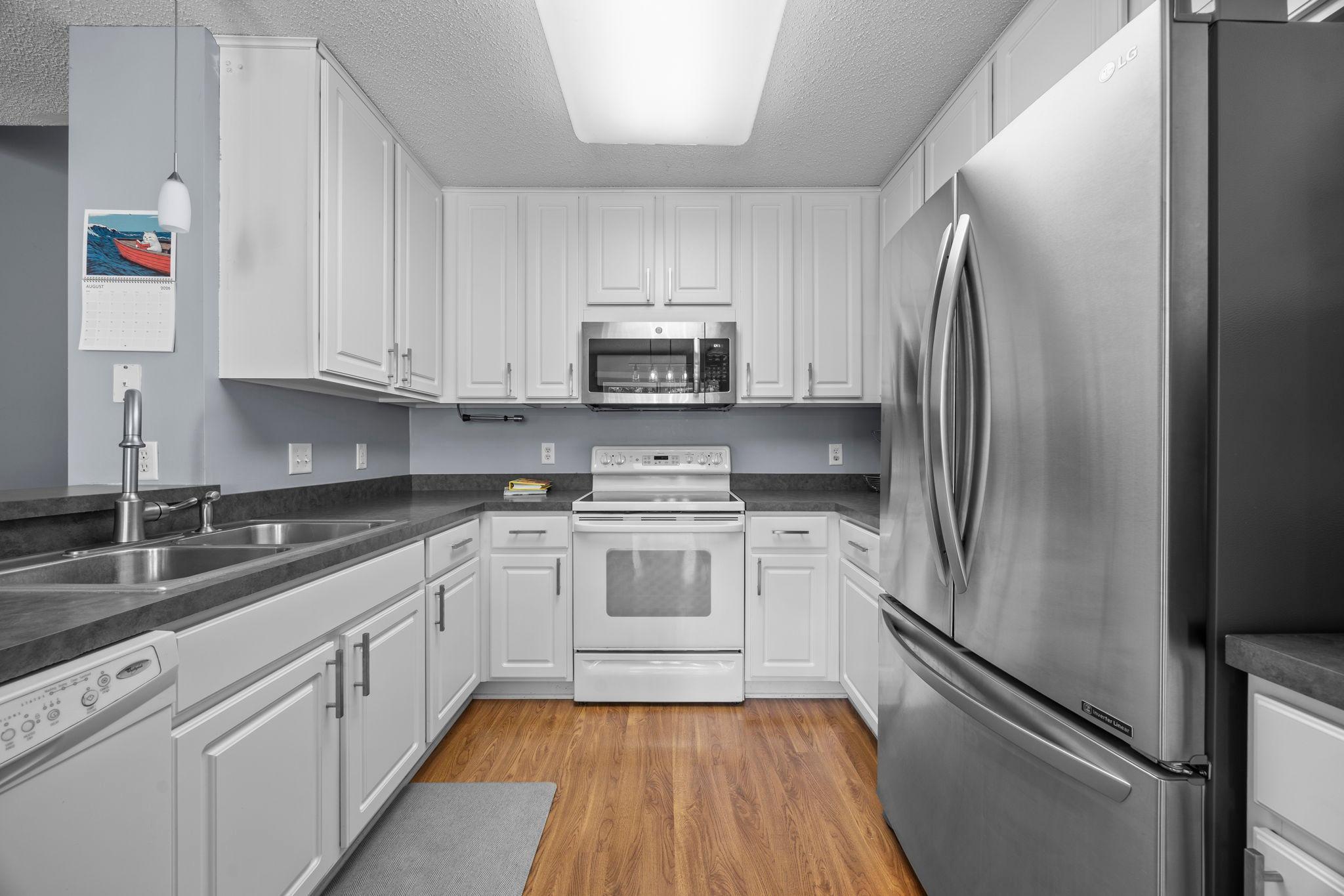 The kitchen offers plentiful white cabinetry and sleek appliances.