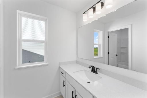 In a well-thought-out design, this full-sized bathroom features a large quartz-topped vanity that can close off from the shower-tub combo in a practical manner.