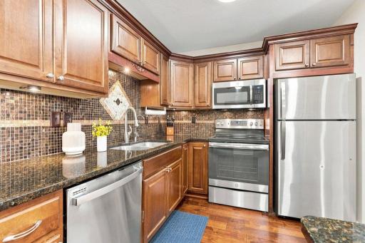 Well-appointed kitchen with granite countertops, mosaic tile backsplash, stainless appliances, and center island with seating.