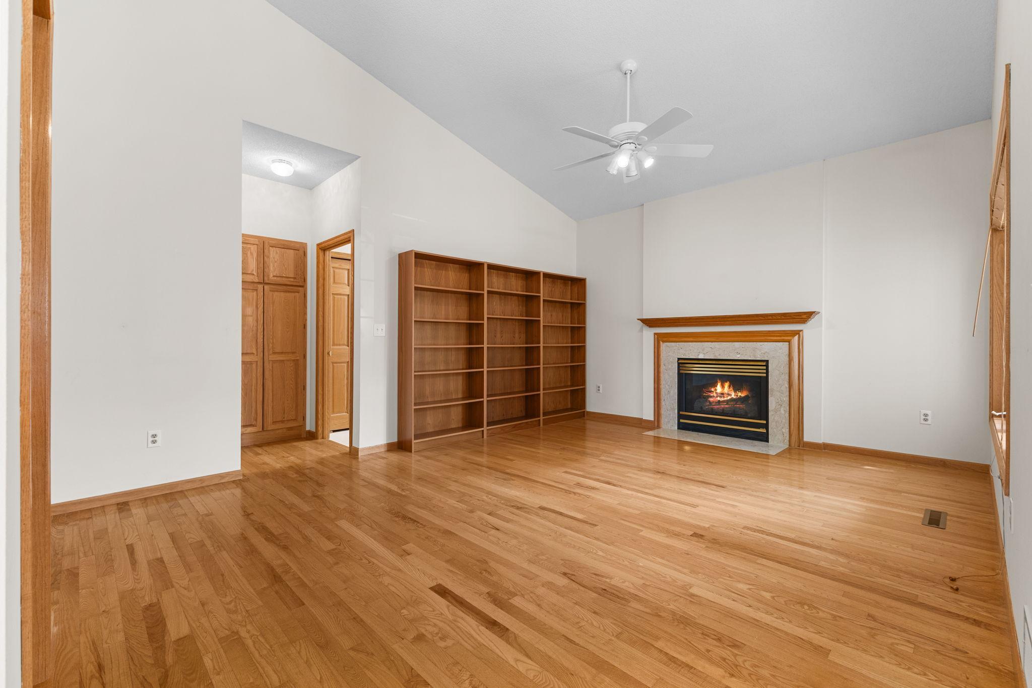 Open living area features vaulted ceilings, hardwood floors, built-ins, and a cozy gas fireplace.
