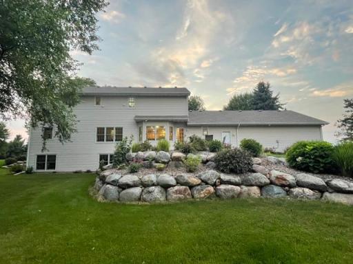 View of back of home. Daylite windows in lower level, boulder wall and planting around the paver patio