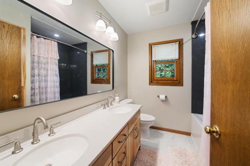 Upper level main bath freshly updated and enhanced with Onyx tub/shower surround to ceiling and on ceiling above tub, two sinks, custom vanity with drawer stacks and linen cabinet Plus a window