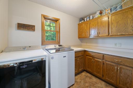 Main level laundry room with built in cabinetry, utility sink, window, clothes chute from primary bedroom