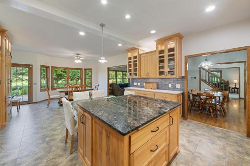 Open and spacious kitchen, with recess lighting, undercabinet lighting highlighting the tiled backsplash and lighting where glass doors are