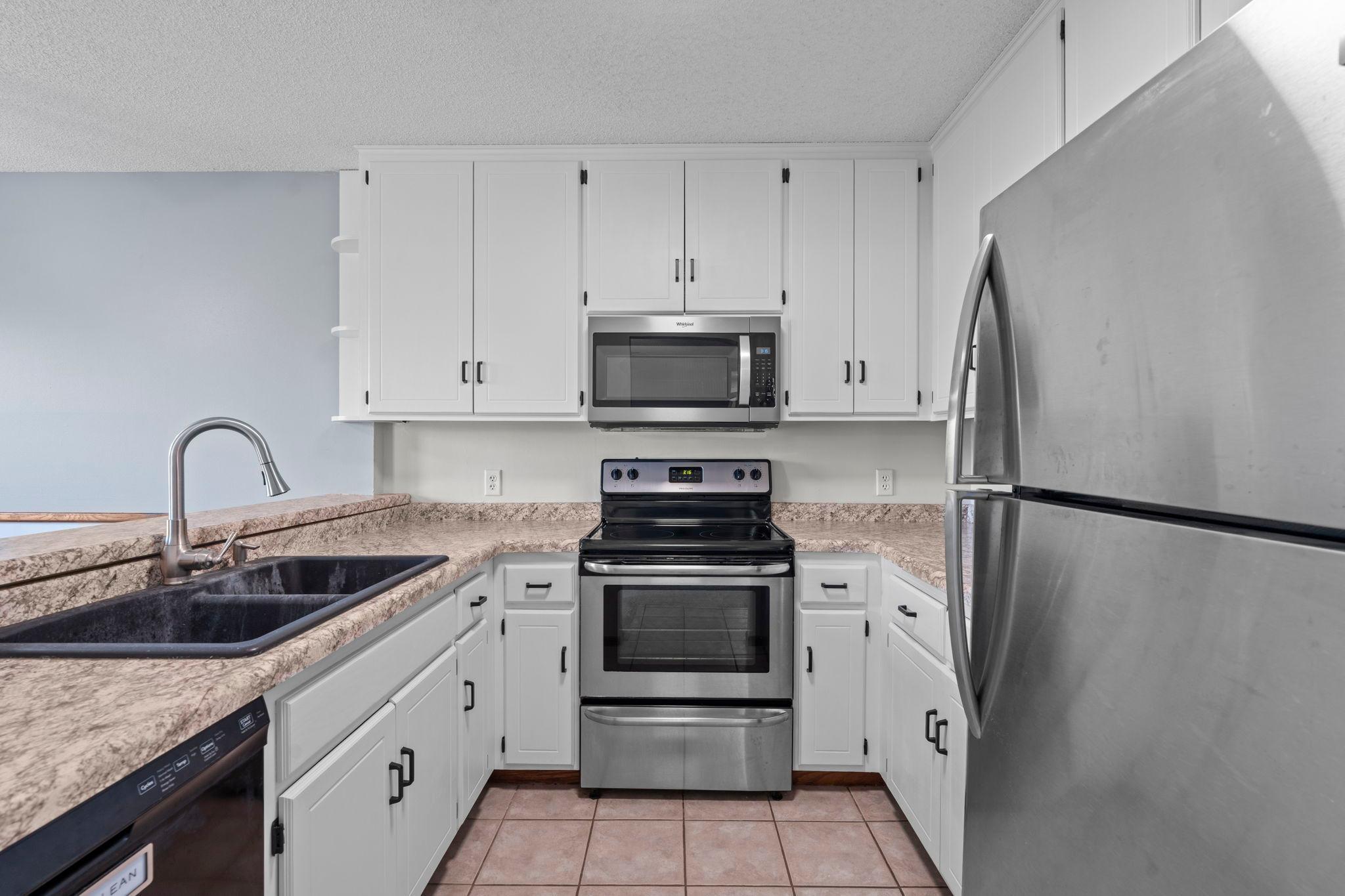 The kitchen, features freshly painted white cabinetry, ample counter space, and a convenient high-top breakfast bar.