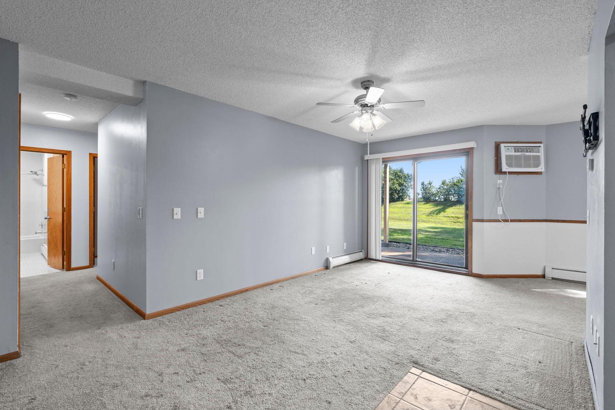 The spacious living room features carpeting, a ceiling fan, and walkout access to a private, south-facing patio.