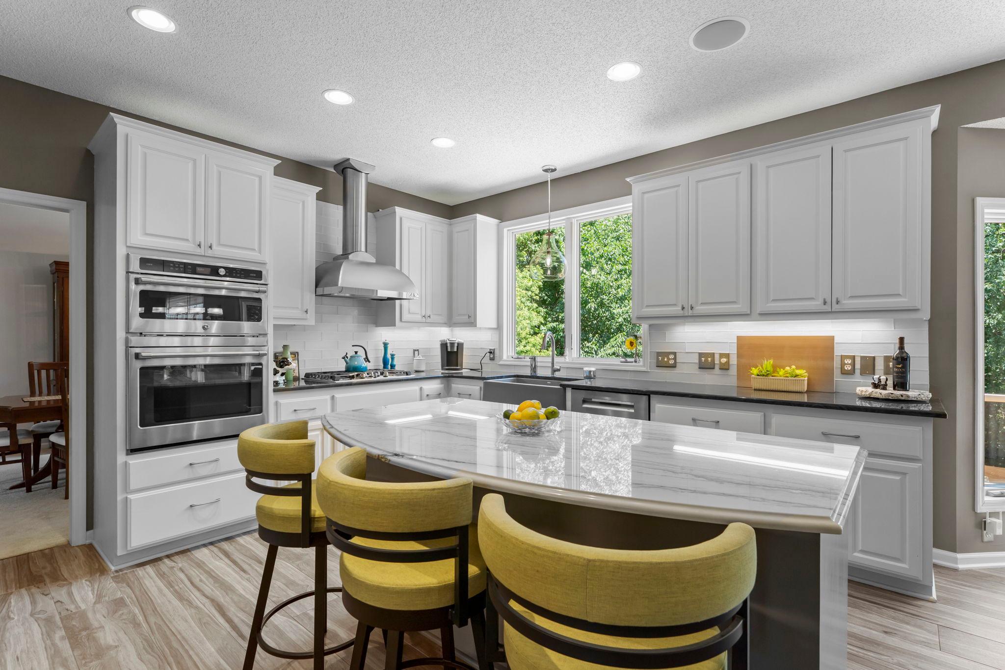 The remodeled 2018 kitchen is truly a chef’s dream, featuring expansive quartzite countertops, a spacious center island with breakfast bar seating, abundant white cabinetry, under-cabinet lighting, and a convenient pantry closet.