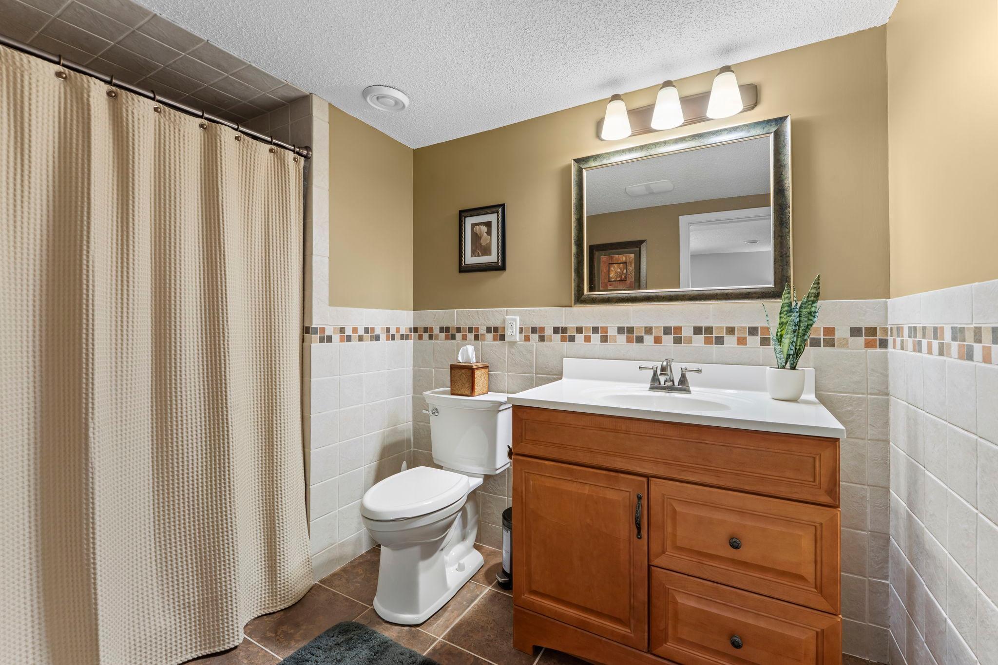 A nearby ¾ bathroom offers tile flooring, a tiled walk-in shower, and single vanity.