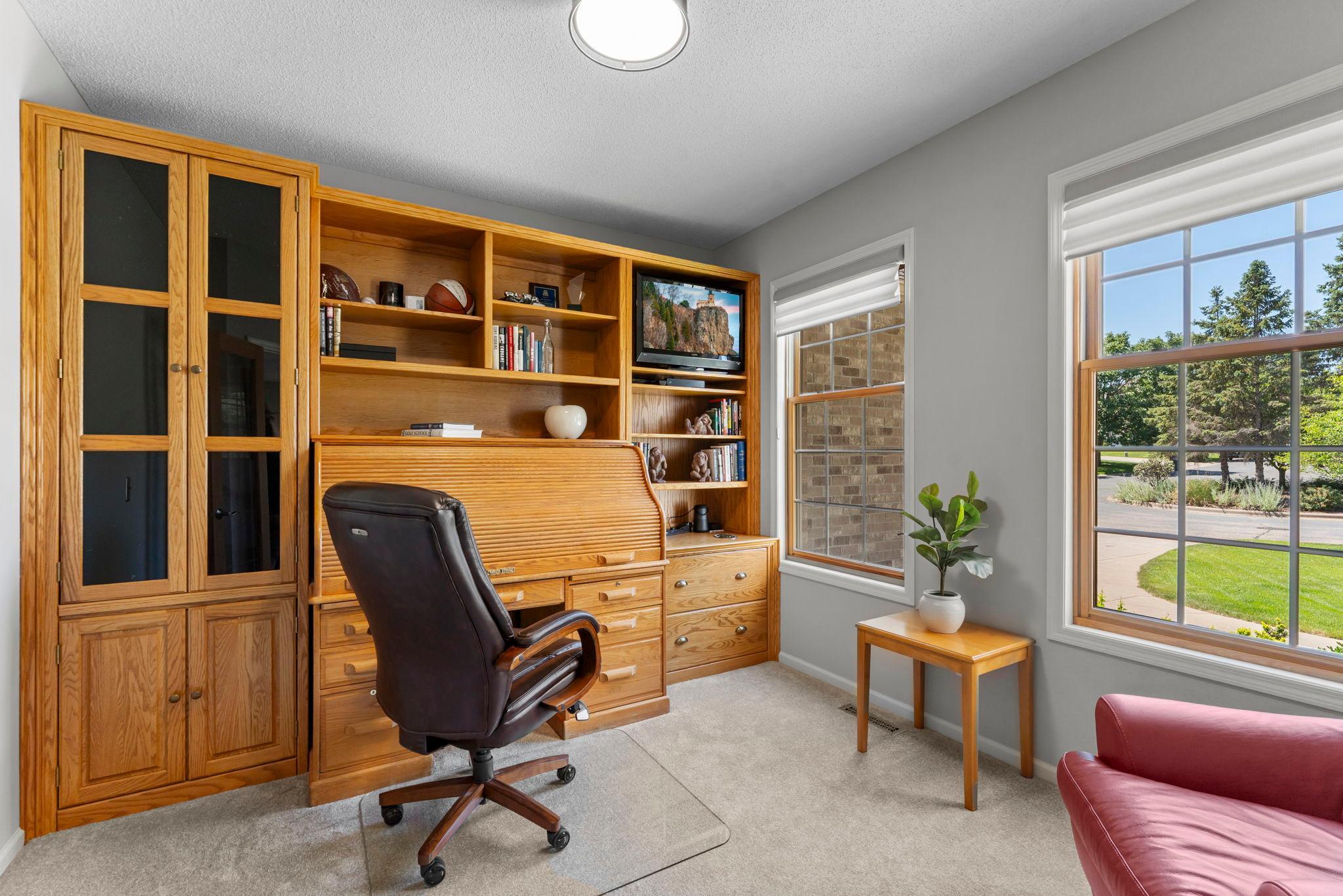 The office offers French double doors, new carpeting, large front-facing windows, and a built-in desk with surrounding storage.