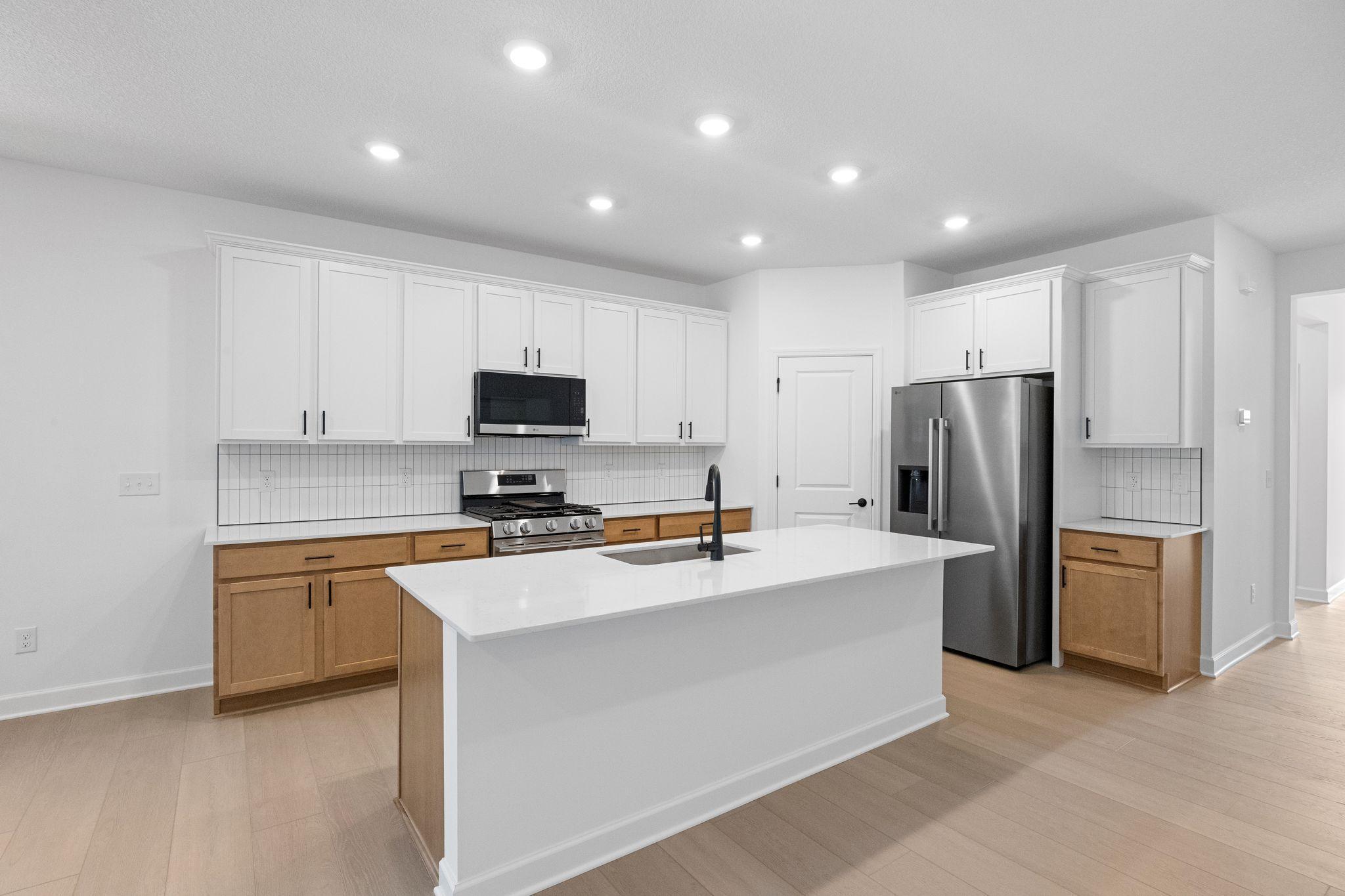 A multifunctional and stylish kitchen complete with a brand-new set of stainless steel appliances, a center island and a convenient corner pantry.