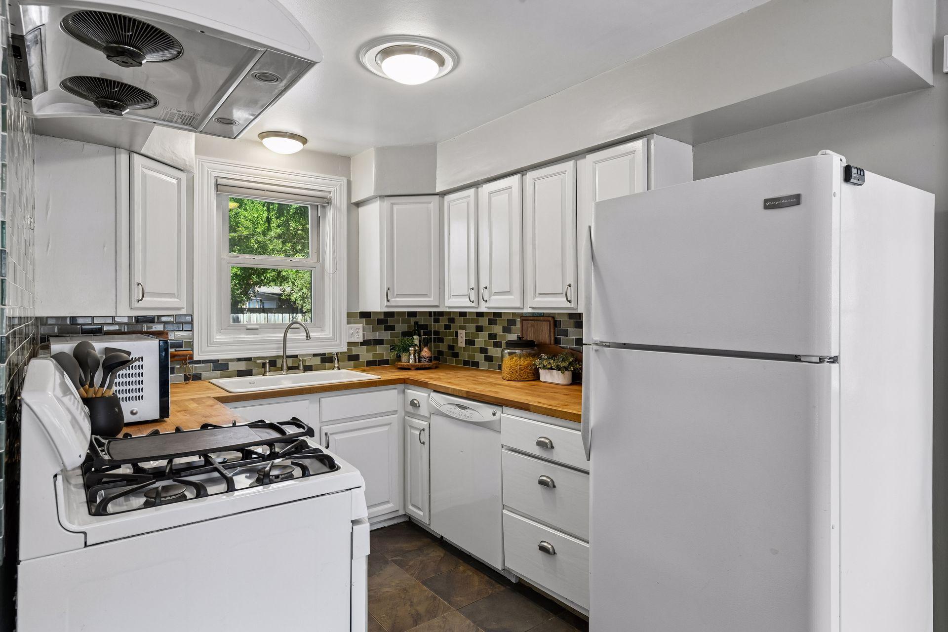 The eat-in kitchen features butcher block countertops and a dining area with windows overlooking the backyard.