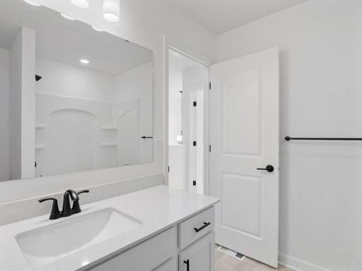 This shared full bathroom includes a full-width vanity mirror and a shower-tub combination.