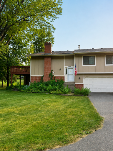 Charming split-level townhome featuring mature trees, classic brick accents, and a spacious two-care garage.