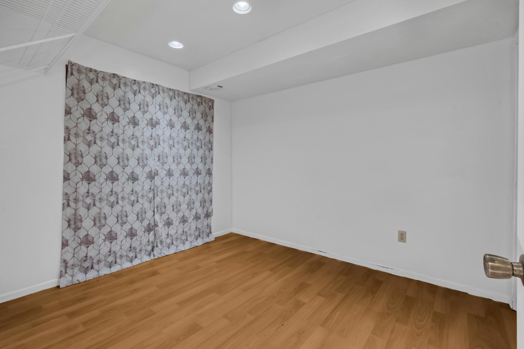 Clean, light-filled bedroom with warm wood-look flooring.