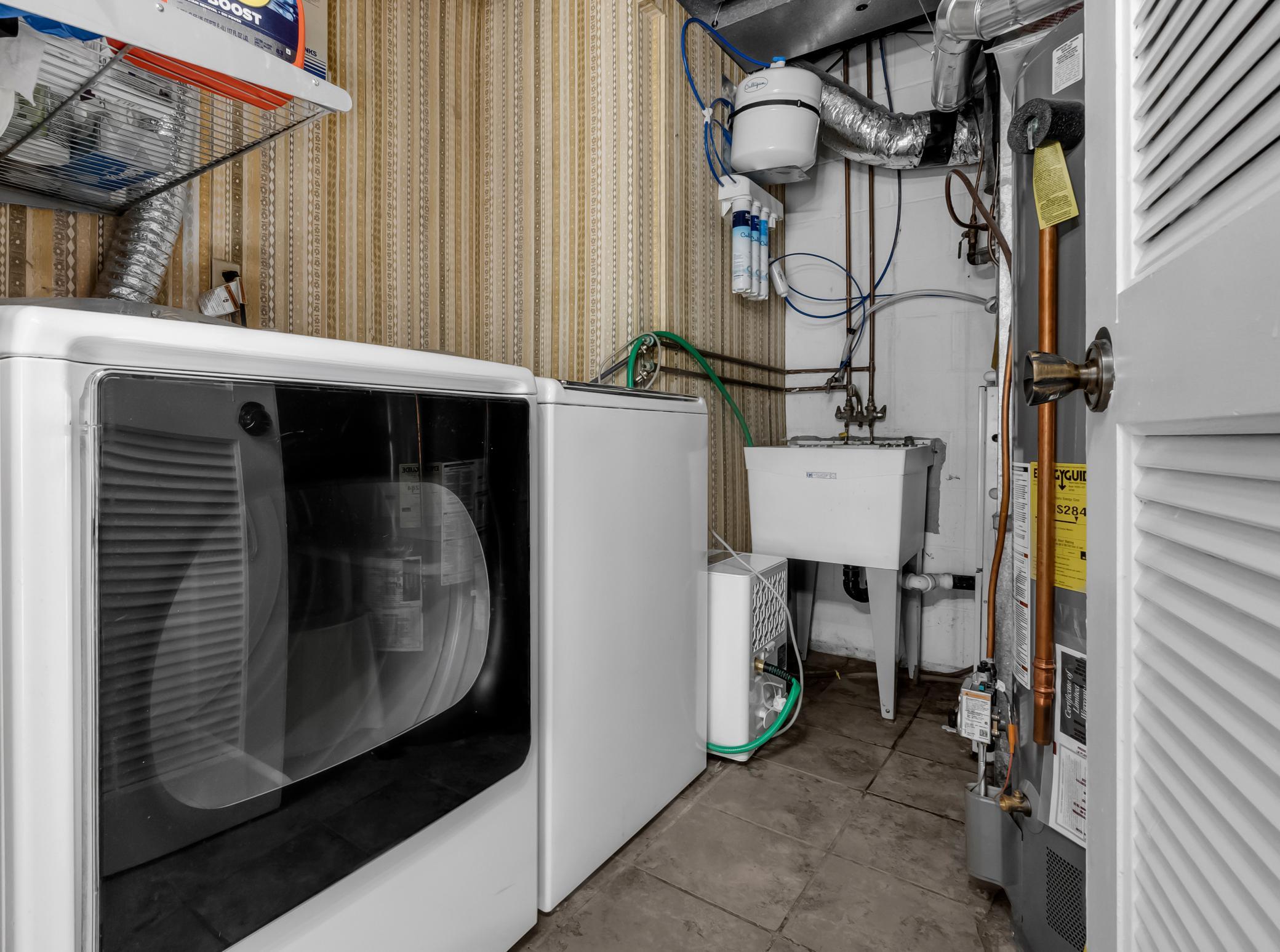 Dedicated laundry and mechanical room equipped with washer, dryer, utility sink, and extra storage room.