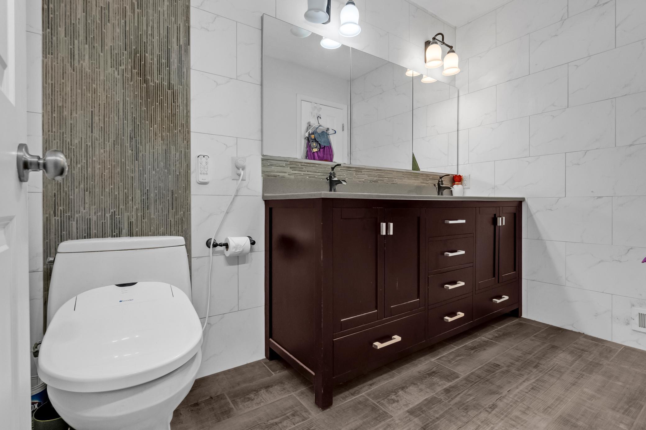 pacious main bathroom featuring a large dark wood double vanity with sleek hardware and ample storage.