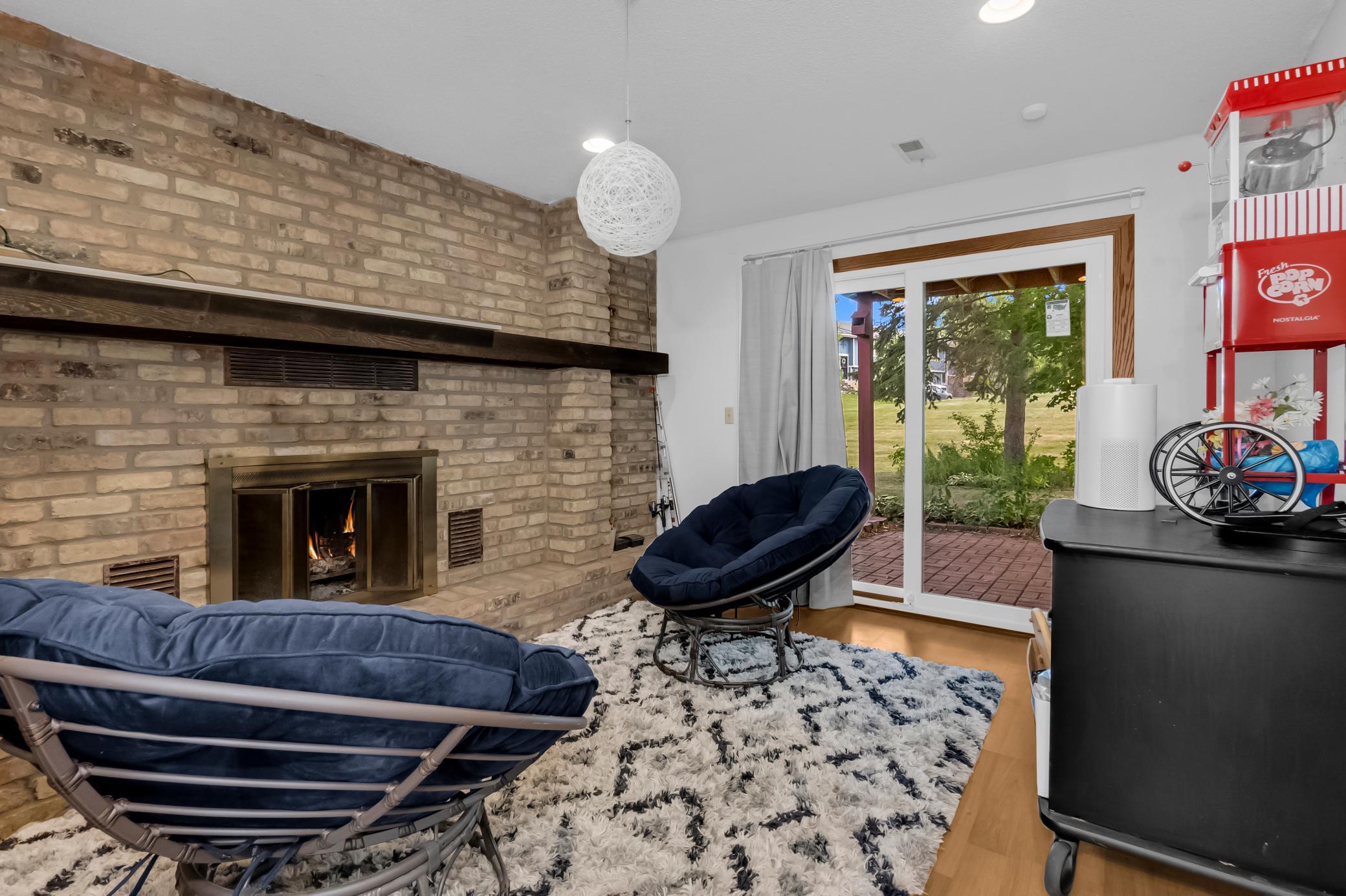 Cozy lower-level family room highlighted by a floor-to-ceiling brick fireplace and sliding glass doors leading outdoors.