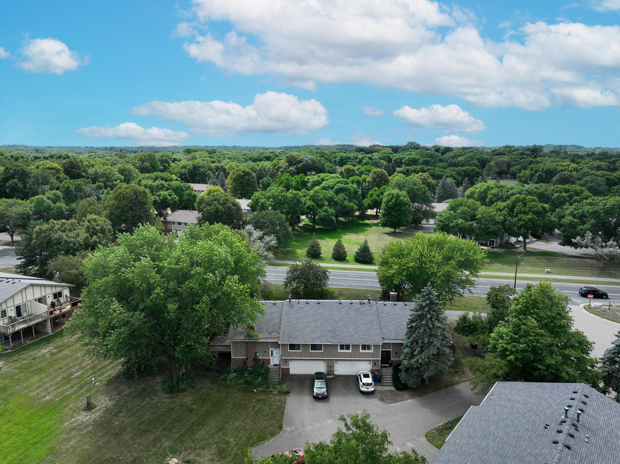 Aerial view showcasing the property surrounded by mature trees and a peaceful residential setting.