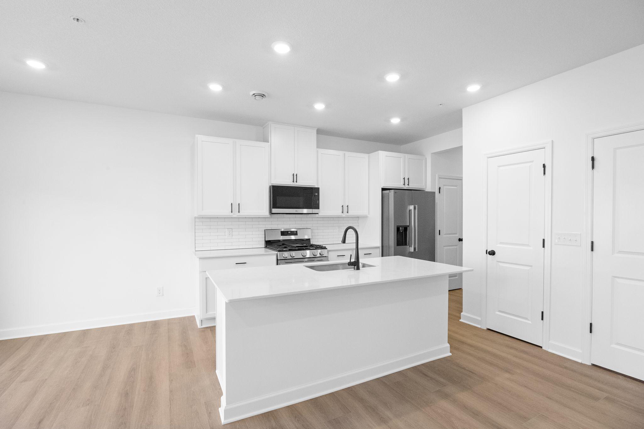 This chef-ready kitchen is designed to accommodate modern living, with a multiuse center island to add food prep and seating space, gleaming quartz countertops and abundant cabinetry room.