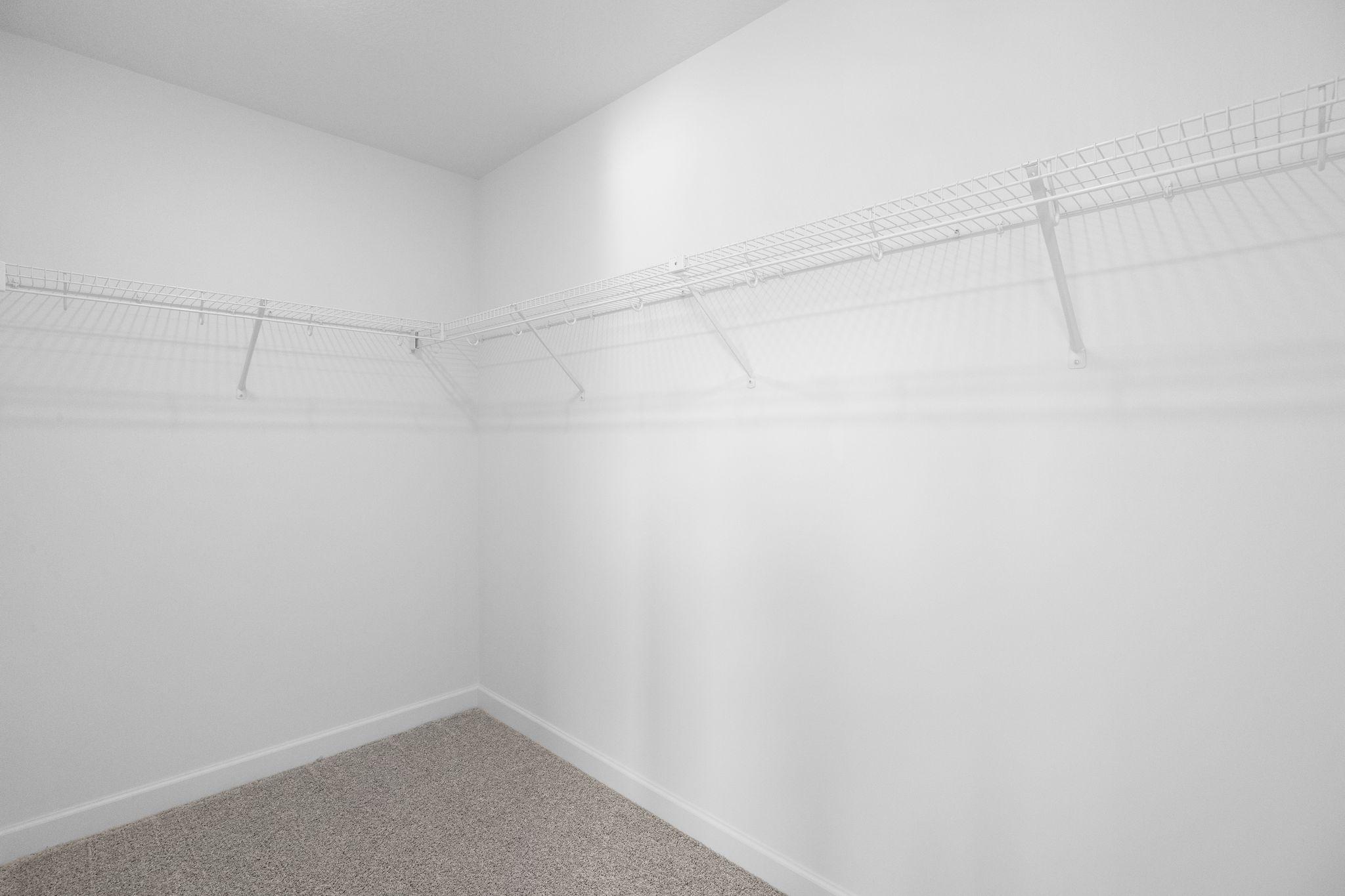 A large walk-in closet with mesh-wire shelving provides abundant room to store wardrobes, shoes, accessories and much more