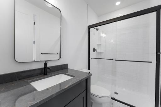 This bathroom is easily accessible from the main living area and bedroom 5, complete with a single vanity and glass-enclosed shower.