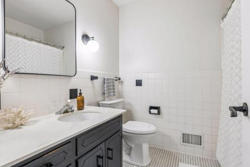 Full bathroom that has been updated with lighting and mirror - neutral tile