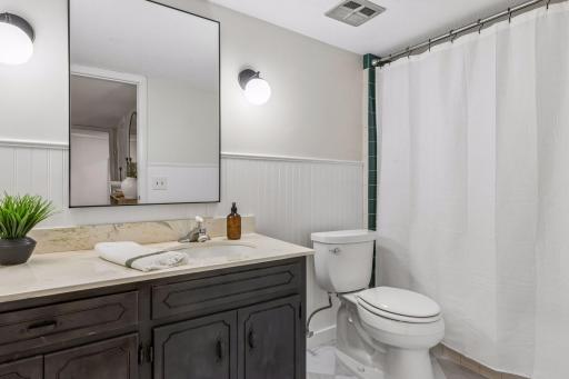 Full bathroom has new flooring, lighting, and mirror