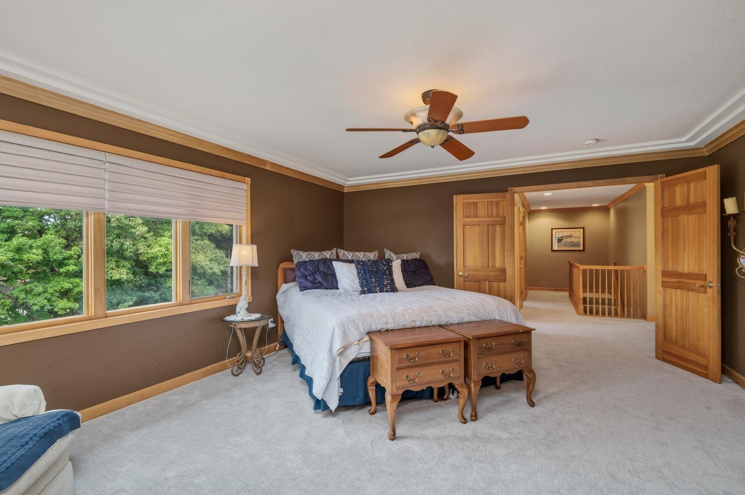 A pair of 6 panel wood doors step into the very spacious primary bedroom suite. The ceiling is finished with cove molding and ceiling fan.