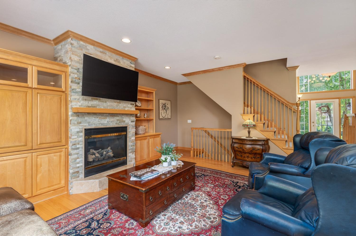 The family room features a gas fireplace with a natural stone surround and custom cabinetry on either side for storage.