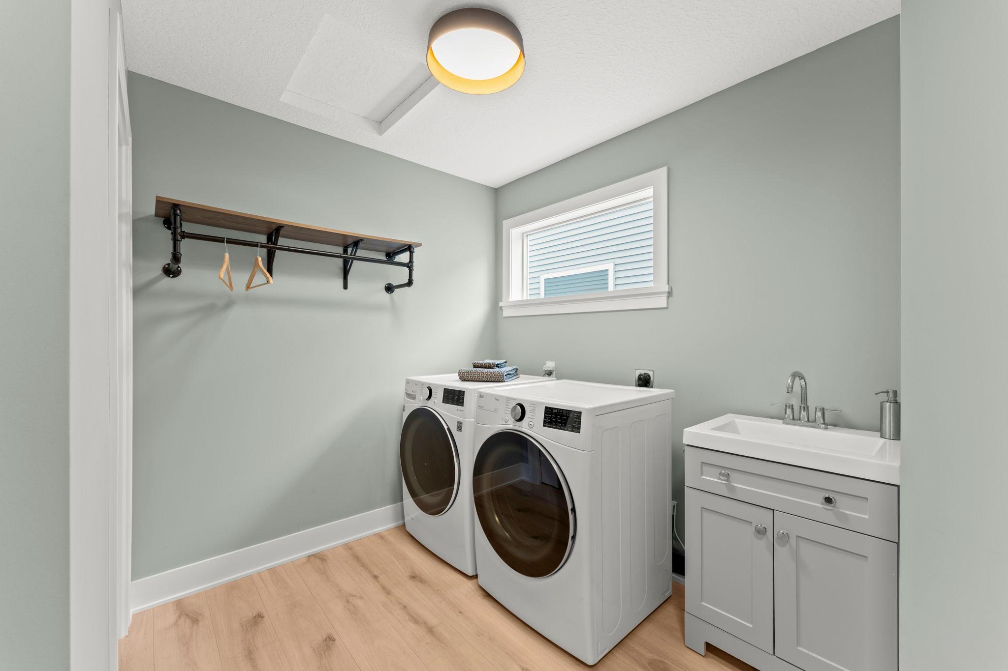 Spacious main level laundry room with cabinetry, a utility sink and additional storage