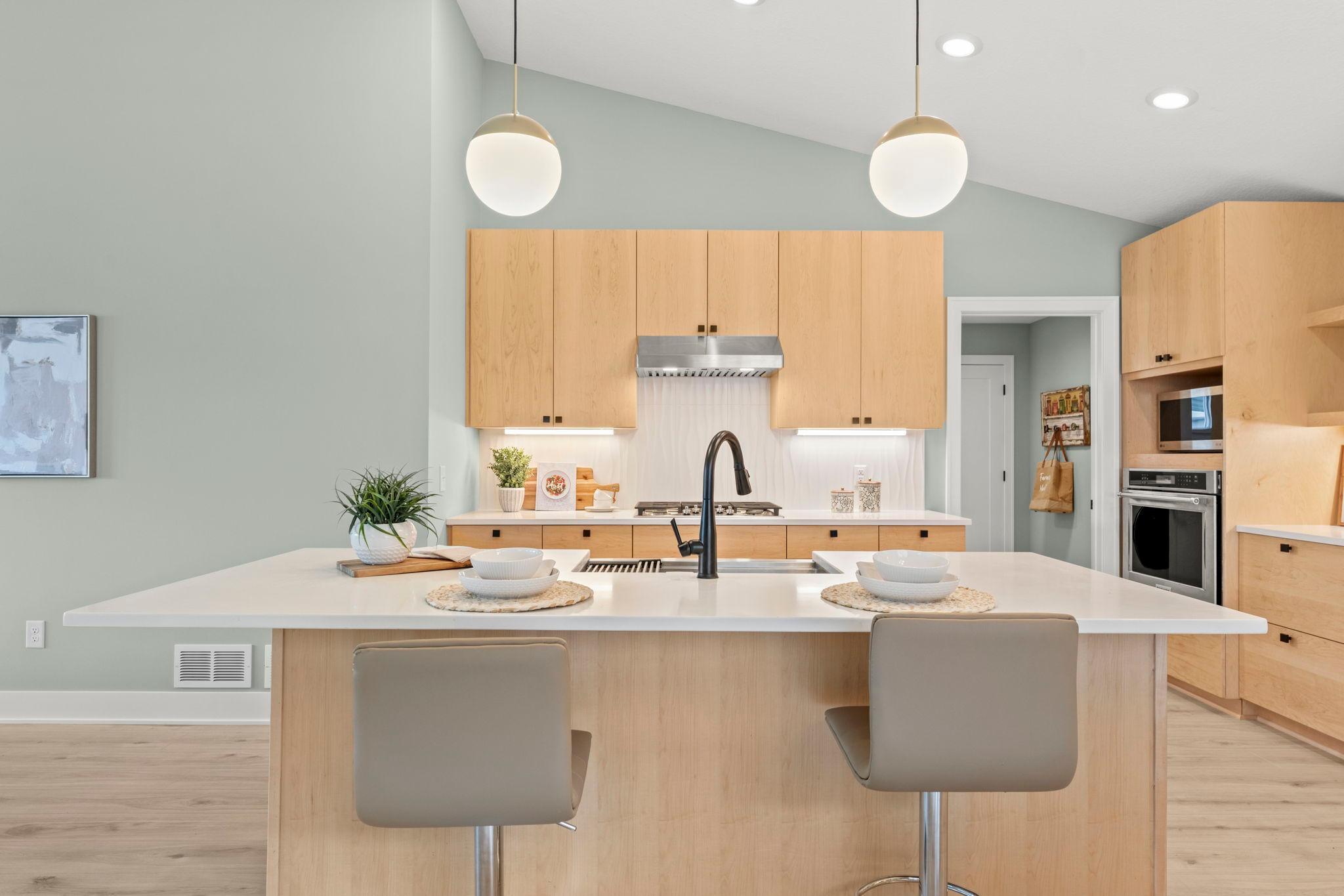 The spacious center island features seating, pendant lighting and a touch activated gooseneck faucet