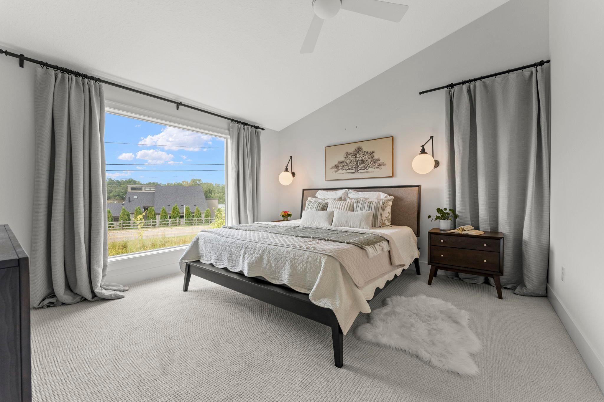 The spacious primary bedroom features a large window with peaceful lake views
