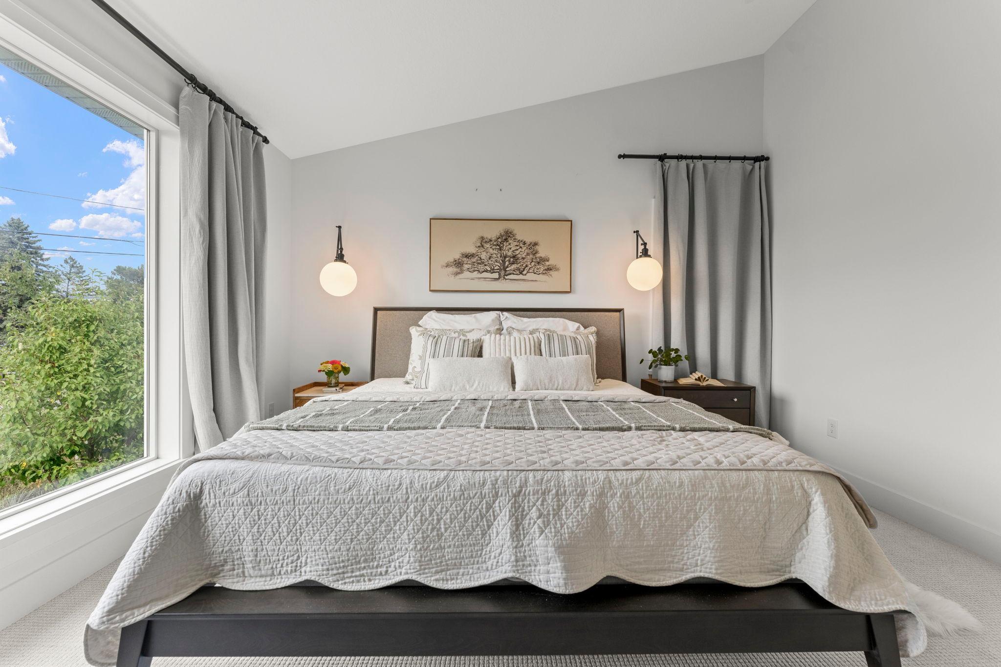 A serene primary bedroom with stylish lighting and plenty of space for a king sized bed