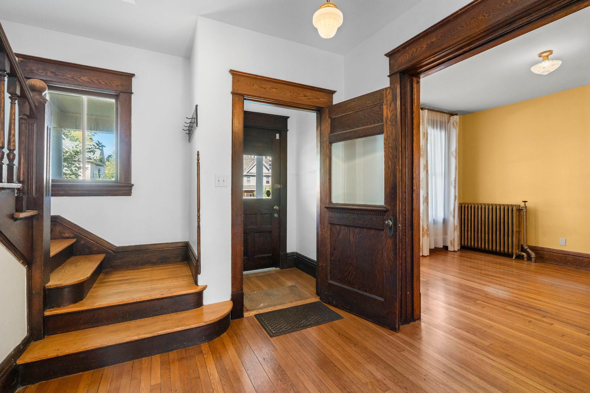 Front hall with view into the living room on the right, the entry vestibule in the middle and stairs to the 2nd floor on the left.
