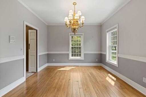 Formal dining room is complete with grid windows, hardwood flooring, and a large chandelier on a dimmer switch.
