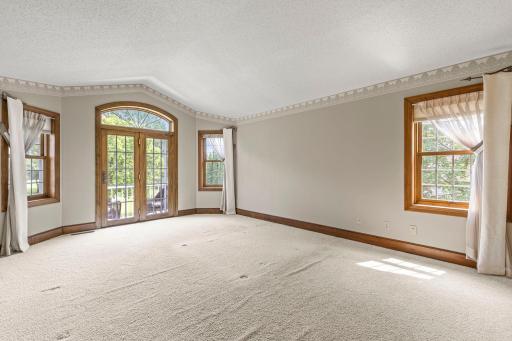 Spacious primary bedroom complete with a balcony, side and backyard veiws, in addition to vaulted ceilings.