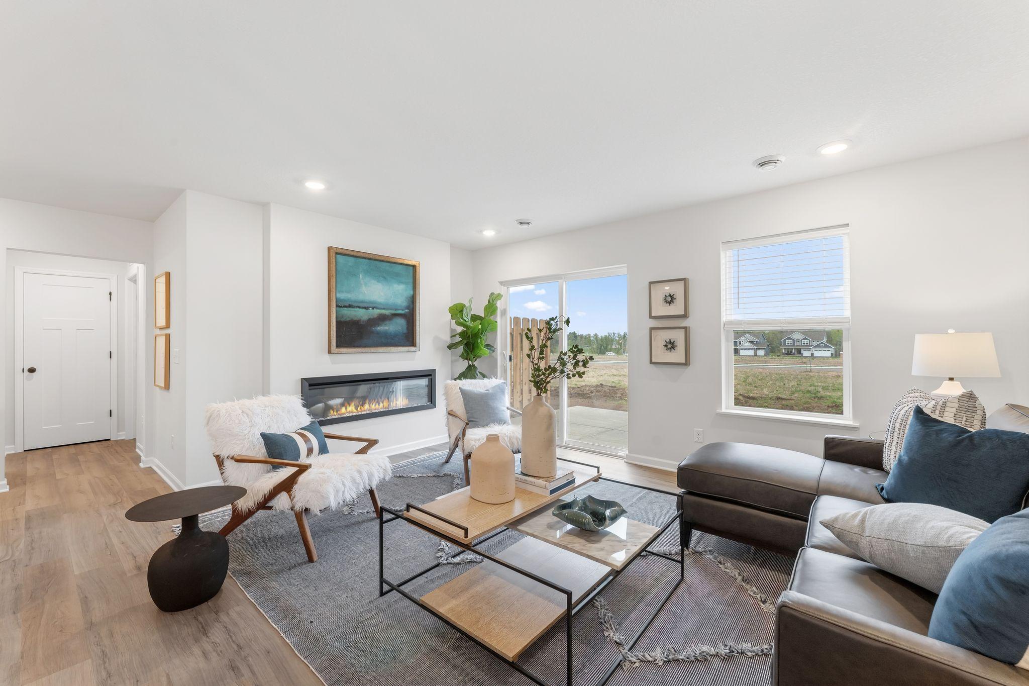 Our newest Trenton plan is a showstopper! The spacious family room features stylish LVP flooring, a low profile fireplace & ample natural lighting! (Picture for representation only, colors and materials may vary in actual home.)