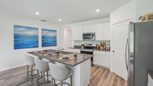 Ample space for seating at the kitchen island. Actual home will include a tile backsplash, quartz countertops, cabinet hardware, soft close drawers and more!
