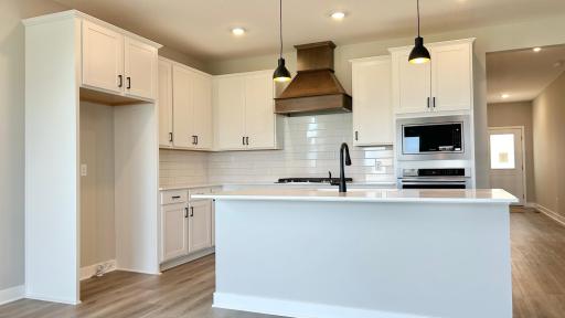 Modern finishes with White and Arid cabinets, quartz countertops, ceramic backsplash and black accents. Photo of actual home.