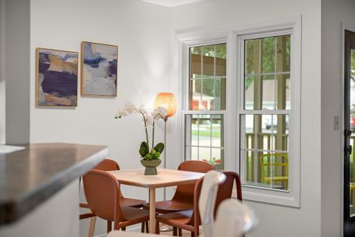 Dining space is positioned beside large windows overlooking the covered porch, creating a bright and inviting place for meals.